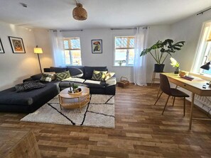 A modern living room with a sofa, coffee table, and a desk area. - 4 Star Holiday Home in Brakne-hoby (Brakne-Hoby)