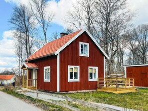 A red wooden house with a sloped roof, a wooden deck, and a small porch. - 4 Star Holiday Home in Brakne-hoby (Brakne-Hoby)