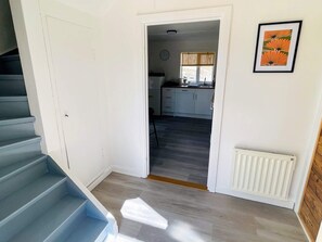 A staircase leading to a room with a white door, a framed picture on the wall, and a kitchen area in the background. - 4 Star Holiday Home in Brakne-hoby (Brakne-Hoby)