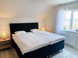 A double bed with a black headboard, two bedside lamps, and a window with curtains. - 4 Star Holiday Home in Brakne-hoby (Brakne-Hoby)