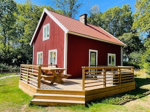 A red wooden house with a tiled roof, a wooden deck, and a picnic table. - 4 Star Holiday Home in Brakne-hoby (Brakne-Hoby)