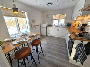 A modern kitchen with a dining area, wooden flooring, and a small refrigerator. - 4 Star Holiday Home in Brakne-hoby (Brakne-Hoby)