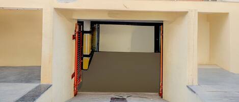 A building entrance with a ramp leading up to a door, surrounded by a beige wall and a metal railing.