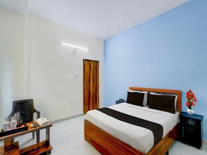 Una camera d'albergo con un letto, un comodino e un tavolino con bollitore e tazze.