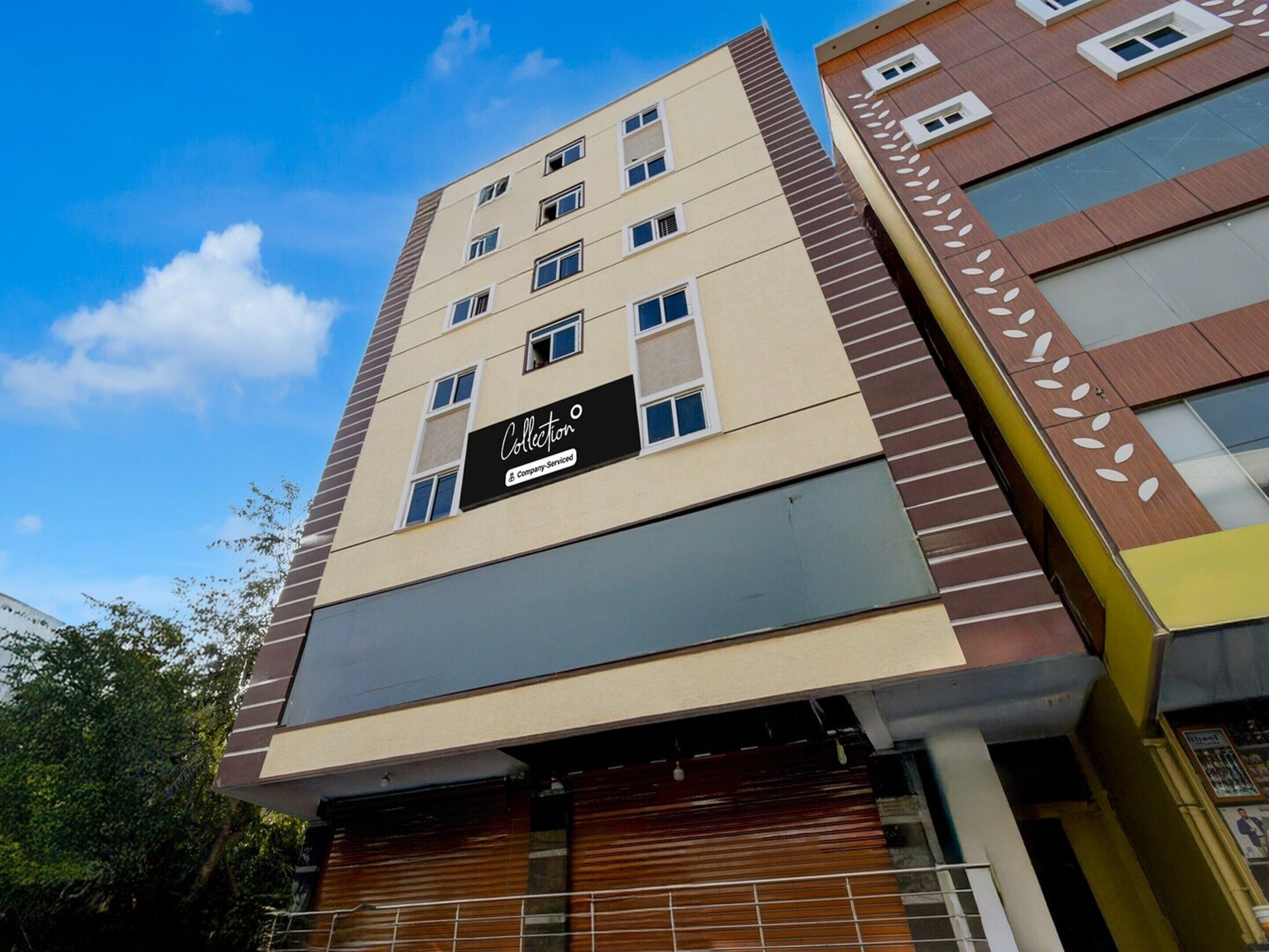 Een meerhoog hotelgebouw met een bord waarop 'Collection' en 'Company-Serviced' staat.