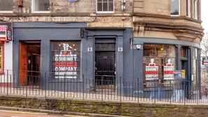 Un edificio con facciata nera, numero 13, e un cartello con la scritta 'Gourmet Mash Bar Company' sulle finestre.