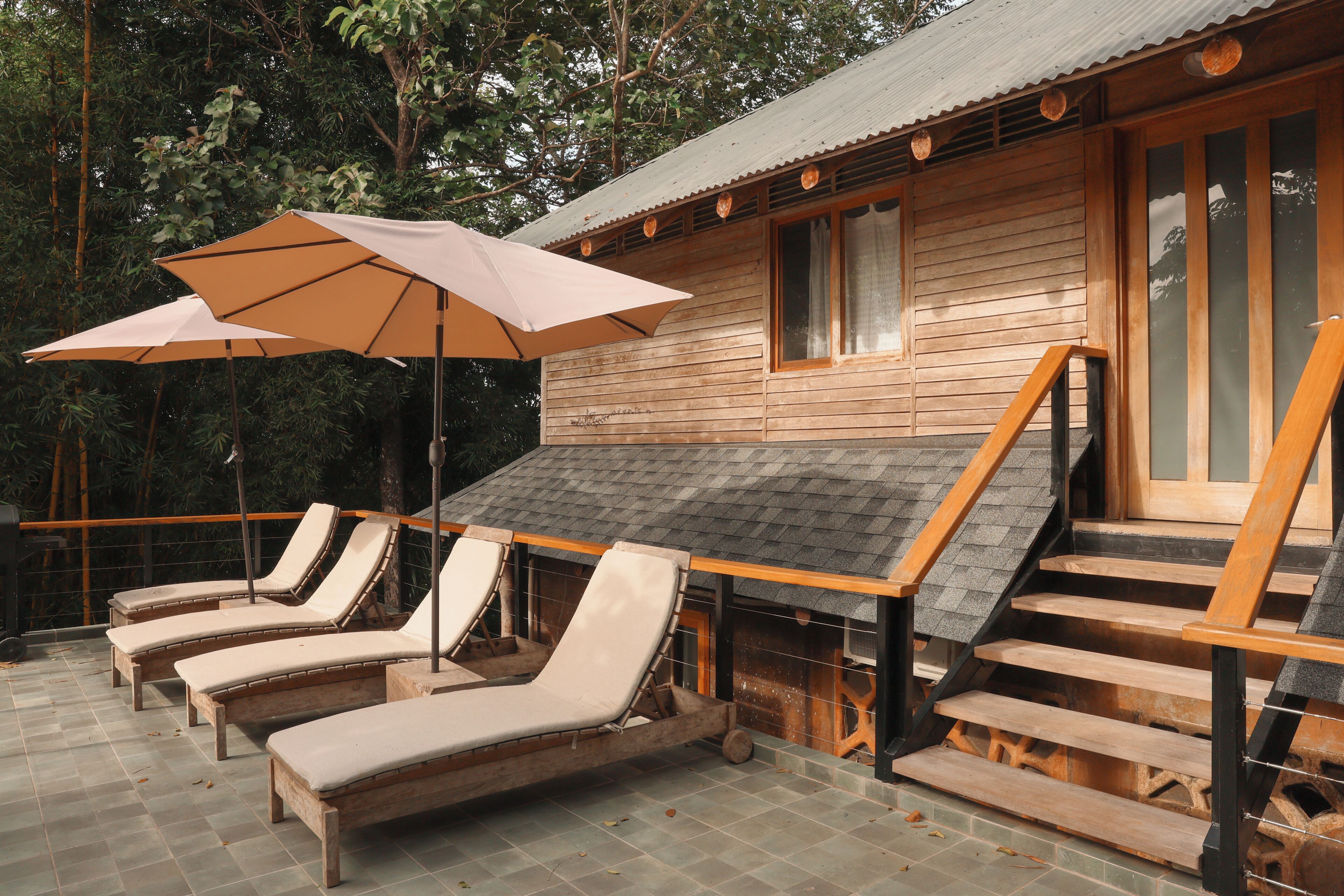 A wooden cabin with a patio area featuring lounge chairs and a large umbrella.