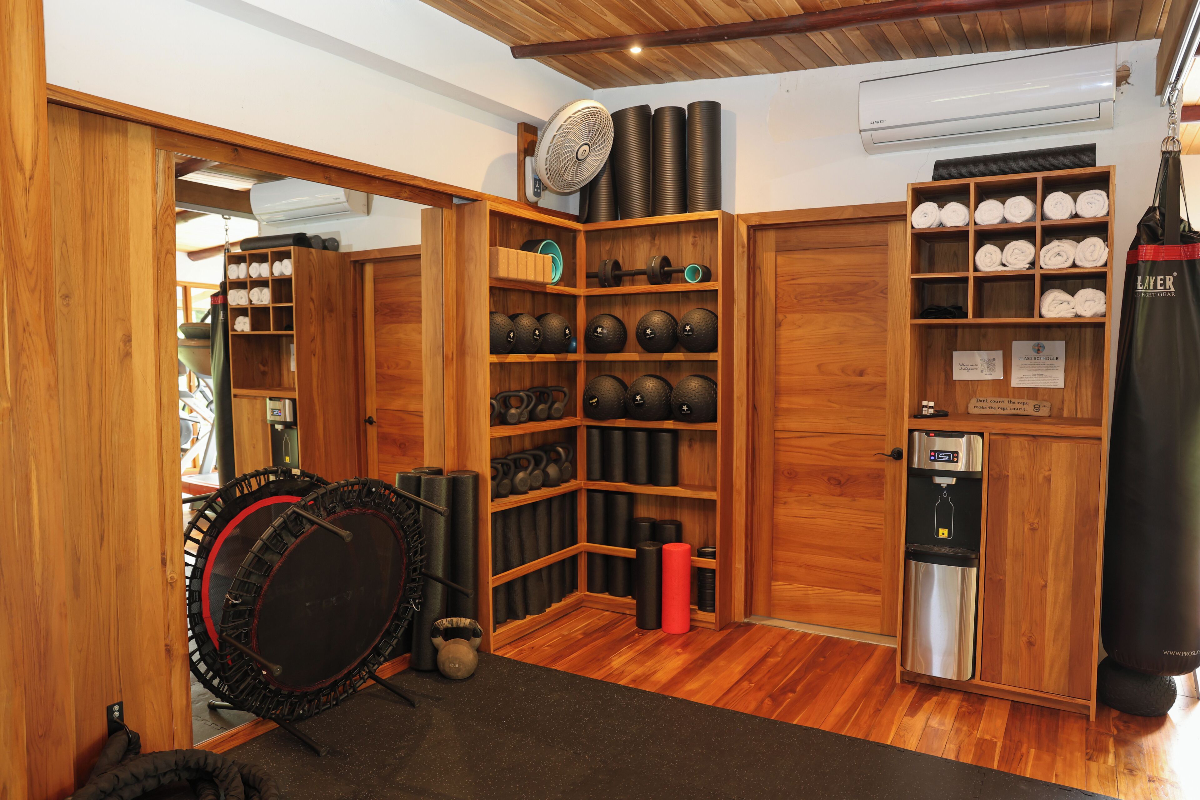 A gym with wooden cabinets, kettlebells, a punching bag, and a water dispenser.
