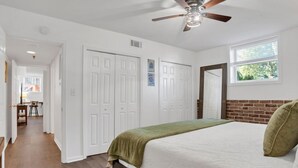 A bedroom with a bed, a ceiling fan, a window, and a door leading to another room. - Rustic Style Apartment, Steps from Forsyth Park (Savannah)