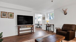 A living room with a TV, wooden furniture, a brown leather chair, and a deer head decoration. - Rustic Style Apartment, Steps from Forsyth Park (Savannah)