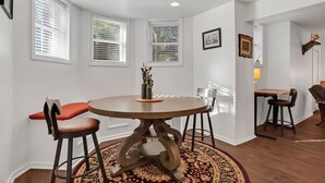 A dining area with a round table, two chairs, a rug, and a window with blinds. - Rustic Style Apartment, Steps from Forsyth Park (Savannah)
