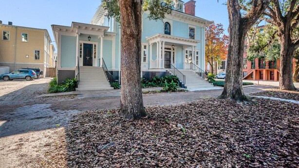 A two-story house with a front porch, a staircase, and a driveway. - Rustic Style Apartment, Steps from Forsyth Park (Savannah)