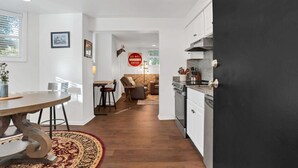 A modern kitchen with a black door, white cabinetry, and a dining area with a round table and chairs. - Rustic Style Apartment, Steps from Forsyth Park (Savannah)