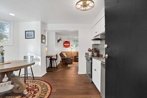 Eine moderne Küche mit einer schwarzen Tür, weißen Schränken und einem Essbereich mit einem runden Tisch und Stühlen.