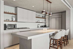 Een moderne keuken met een centraal eiland, barstoelen en hanglampen.