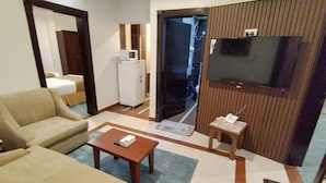 A living room with a sofa, a coffee table, a TV, and a microwave. - Ferbion Hotel Abha (Abha)