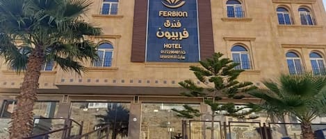 A hotel facade with a large sign, multiple windows, and a staircase leading to the entrance.