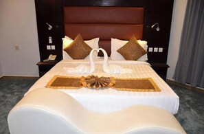 Habitación de hotel con una cama grande, cabecero, mesitas de noche, teléfono y toma de corriente.