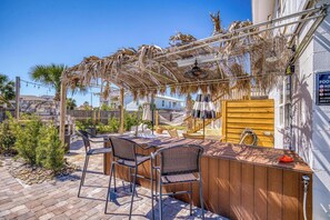 An outdoor bar area with a wooden counter and metal chairs, a pergola with dried palm fronds, and a sign indicating no swimming. - 🌴☀️Private Pool | Backyard Oasis w/ Fireplace | Pet Friendly 🐾 Largo 802 (Pensacola Beach)