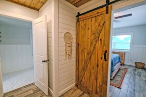 A room with a wooden sliding door, a bed with a blue blanket, and a window with blinds. - 🌴☀️Private Pool | Backyard Oasis w/ Fireplace | Pet Friendly 🐾 Largo 802 (Pensacola Beach)