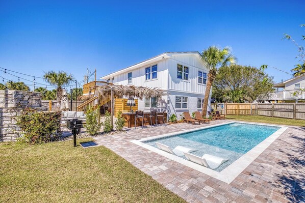 A two-story house with a swimming pool, outdoor seating, and a stone wall. - 🌴☀️Private Pool | Backyard Oasis w/ Fireplace | Pet Friendly 🐾 Largo 802 (Pensacola Beach)