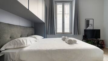Una camera da letto moderna con un letto grande, una televisione a schermo piatto e una finestra con tende.