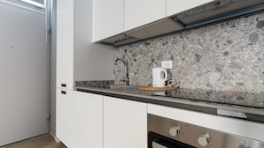 Una cucina moderna con mobili bianchi, un piano di lavoro in granito, una macchina da caffè e un forno integrato.