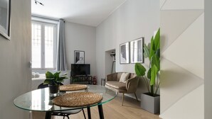 Un soggiorno moderno con un tavolo da pranzo in vetro, un divano, una televisione e quadri appesi al muro.
