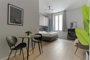 A modern bedroom with a bed, a small table with chairs, a TV, and a large green plant. - Cozy 37m2 studio apartment, perfect for two people, located on the ground floor of a building (1 step to access).The accommodation is located a stone's throw from Crescenzago and the M2 metro stop of the same name, making it strategically ideal for reach (Milan)