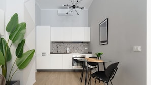 Una cucina moderna con mobili bianchi, un piano di lavoro in granito e un'area pranzo con un tavolo rotondo e sedie nere.