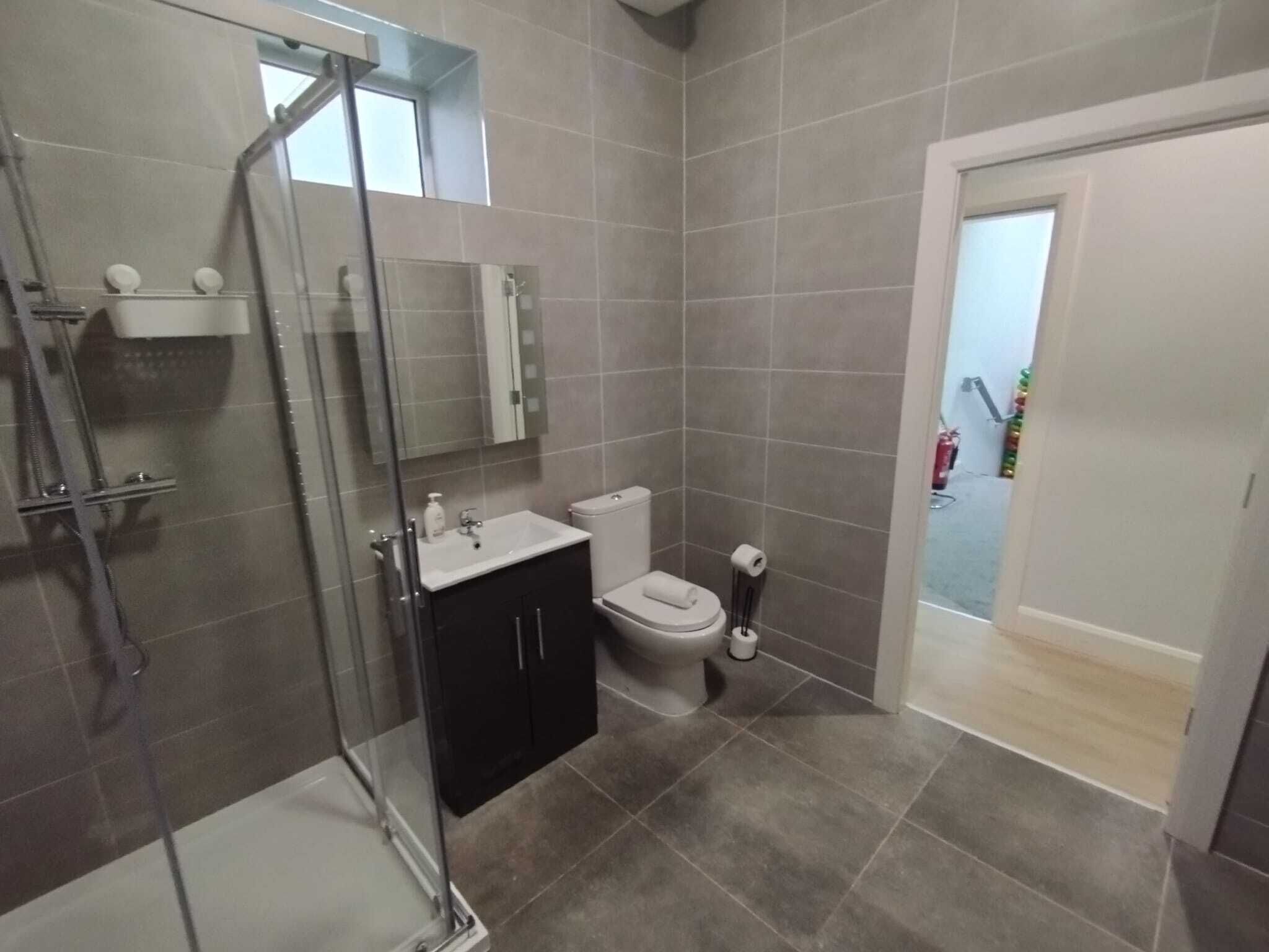 A modern bathroom with a glass-enclosed shower, a white sink, and a toilet.