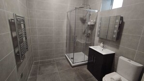 Ein modernes Badezimmer mit einer gläsernen Duschkabine, einem Waschtisch und einer Toilette.