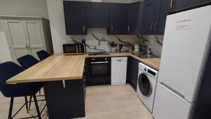 Eine kleine Küche mit dunklen Schränken, einer Holz Arbeitsplatte, einer Mikrowelle, einem Geschirrspüler und einer Waschmaschine.
