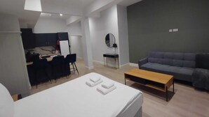 Ein modernes Zimmer mit Bett, Schreibtisch, Sofa und Spiegel.