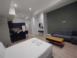 Ein modernes Zimmer mit Bett, Schreibtisch, Sofa und Spiegel.