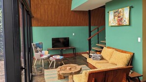 A modern living room with a sofa, a television, a chair, and a staircase.