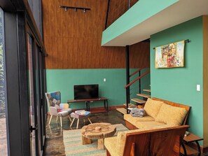A modern living room with a sofa, a television, a chair, and a staircase.