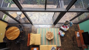 A spacious room with a large glass ceiling, a round wooden table, a sofa set, and a patterned rug.