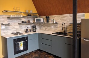 A modern kitchen with a gas stove, microwave, coffee maker, and a sink.
