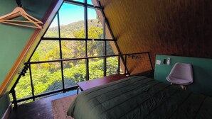 A room with a sloped ceiling, a bed, a table, and a chair.