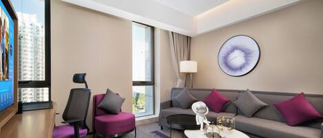 Et moderne hotelværelse med et stort vindue, en sofa, en stol, et sofabord og et vægur.