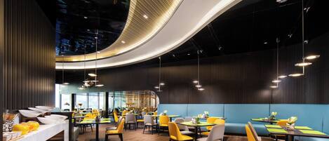 Un ristorante moderno con soffitto curvo, pavimento in legno e sedute gialle e grigie.