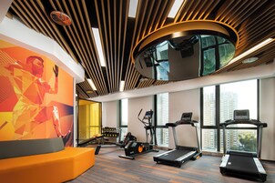 A gym with treadmills, an elliptical, and a wall with a geometric design.