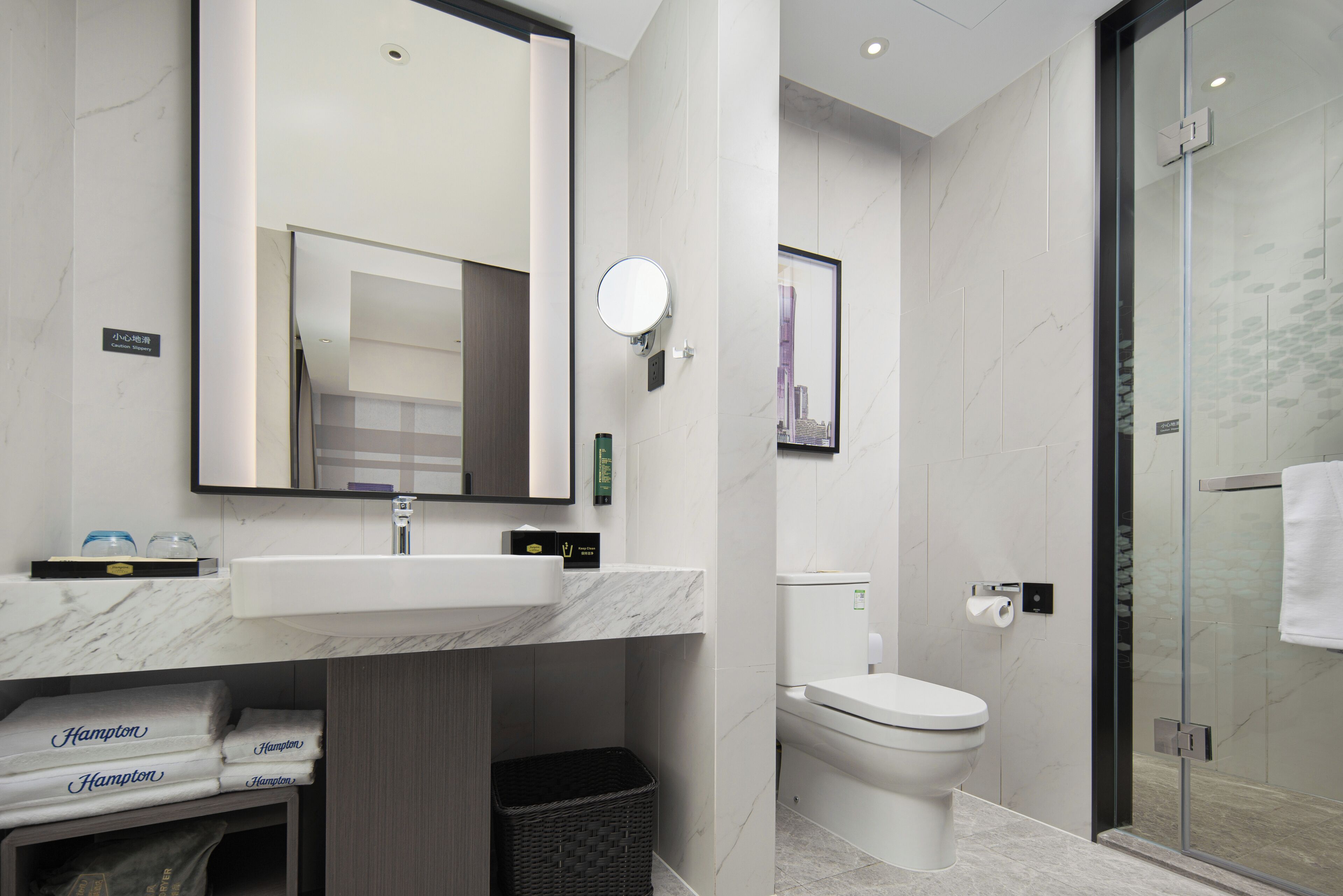 Un baño moderno con lavamanos de mármol, inodoro y cabina de ducha con paredes de vidrio.