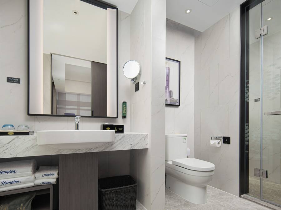 Un baño moderno con lavamanos de mármol, inodoro y cabina de ducha con paredes de vidrio.