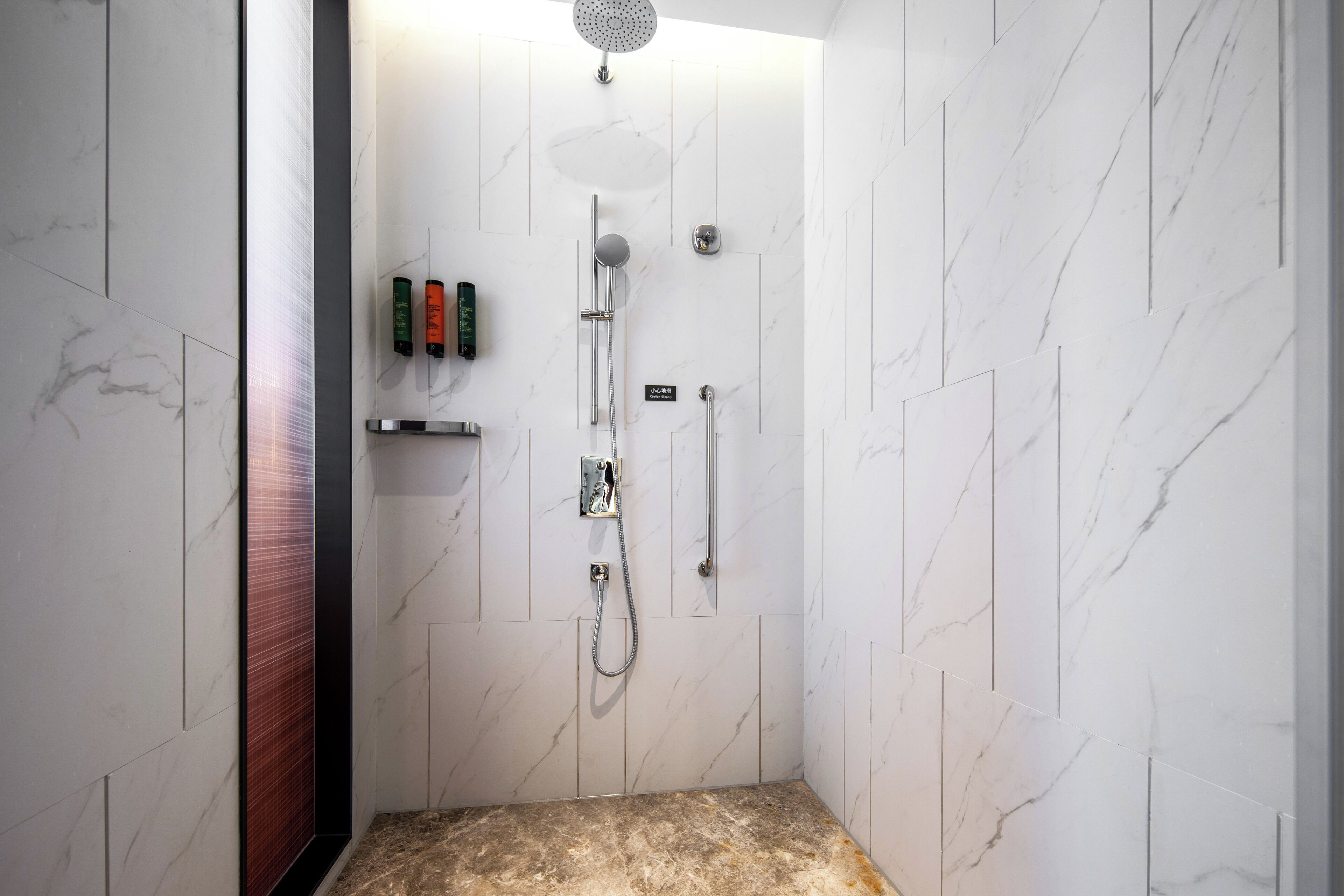A modern shower with a handheld showerhead, a wall-mounted faucet, and a handheld showerhead.