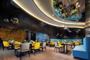 A modern restaurant with a curved ceiling, yellow and grey chairs, and tables.
