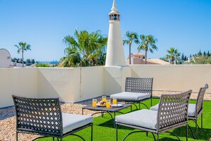A rooftop terrace with outdoor seating, a lighthouse in the background, and a clear view of the sea. - Casa do Livramento - Fabulous 3 bedroom villa with games room (Carvoeiro)
