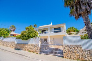 A two-story house with a stone wall, a metal gate, and a clear blue sky. - Casa do Livramento - Fabulous 3 bedroom villa with games room (Carvoeiro)