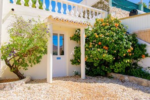 A white building with a covered entrance, a 'PRIVADO' sign, and a garden with flowering plants. - Casa do Livramento - Fabulous 3 bedroom villa with games room (Carvoeiro)